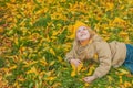 a little girl lies on a lawn covered with yellow autumn leaves and looks up with a smile on her face The girl is happy Royalty Free Stock Photo