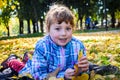 Little girl lies on leaves in autumn park. A beautiful child is in the background of the yellow leaves of the city park Royalty Free Stock Photo
