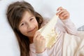 The little girl lies sick in bed, in the hands of a napkin, girl smiles Royalty Free Stock Photo