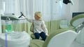 Little girl lifts up dental chair in clinic