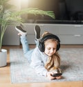 Little girl listening music lying on the floor Royalty Free Stock Photo