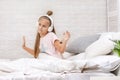 Little girl listening to the music with the headphones on bed. Royalty Free Stock Photo