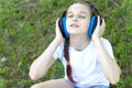 Little girl listening to music in her headphones in the park on the grass. Royalty Free Stock Photo