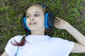 Little girl listening to music in her headphones in the park on the grass. Royalty Free Stock Photo