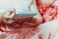 Little girl little girl in a beautiful fluffy pink skirt with ruffles use white mobile phone. Royalty Free Stock Photo