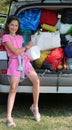 Little girl loads her purse in the car trunk Royalty Free Stock Photo