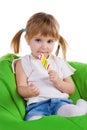 Little girl with lollipop sit on green armchair Royalty Free Stock Photo