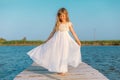 Little girl with long blond hair sitting on the pier Royalty Free Stock Photo