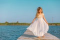 Little girl with long blond hair sitting on the pier Royalty Free Stock Photo