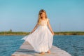 Little girl with long blond hair sitting on the pier Royalty Free Stock Photo