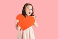 Pretty little girl with long curly hair hold in hand big red paper heart opening mouth surprisingly on pink background. Royalty Free Stock Photo