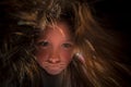 A little girl with long, disheveled hair looks like a witch. A terrible and frightening children`s witchcraft portrait. A child i Royalty Free Stock Photo