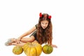 Little girl with long hair in a devil dress in a dress with horns on Halloween with pumpkins Royalty Free Stock Photo