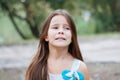 Little girl with long hair portrait, emotionally crying and upset, natural lighting outside