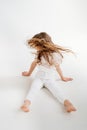 little girl with long hair sits on floor, and waving his head, hair is flying