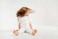 little girl with long hair sits on floor, and waving his head, hair is flying