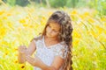 Little girl with long hair in a white dress rejoices in a field with flowers