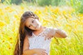 Little girl with long hair in a white dress rejoices in a field with flowers