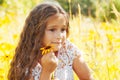 Little girl with long hair in a white dress rejoices in a field with flowers Royalty Free Stock Photo