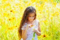 Little girl with long hair in a white dress rejoices in a field with flowers Royalty Free Stock Photo