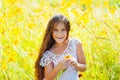 Little girl with long hair in a white dress rejoices in a field with flowers Royalty Free Stock Photo