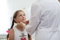 Little girl looking at doctor who testing her tonsils