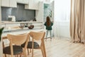 A little girl wearing green sweater and lightblue jeans is looking into a fridge in a bright kitchen while standing with Royalty Free Stock Photo