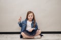 Little girl looking happy, confident and trustworthy, smiling and showing victory sign, with a positive attitude sitting on the Royalty Free Stock Photo