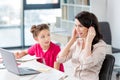Little girl looking at happy mother in headset working with laptop Royalty Free Stock Photo