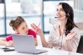 Little girl looking at happy mother in headset working in office Royalty Free Stock Photo