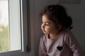 Beautiful little girl smiling and watching out the window. A child looks out the window. Royalty Free Stock Photo