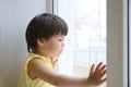 Little girl looking out the window longing for some sunshine. child sitting home at rainy day Royalty Free Stock Photo