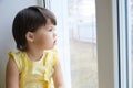 Little girl looking out the window longing for some sunshine. child sitting home at rainy day Royalty Free Stock Photo