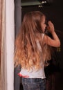 Little girl looking out window while standing on windowsill Royalty Free Stock Photo