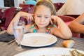 Little girl looking with sad expression face at a plate with fish cooked