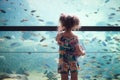 A little girl looking at tropical colorful fish in a big tank at an aquarium Royalty Free Stock Photo