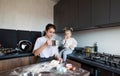 a little girl looks attentively at her mother in the kitchen who is making cookies from flour. joint cooking Royalty Free Stock Photo