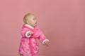 Little girl looks away in a pink bathrobe on a pink background in the studio Royalty Free Stock Photo