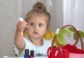 Little girl looks at a bottle of nail polish in surprise Royalty Free Stock Photo