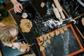 Little girl looks at the cookie cutters on the dough on the table while sitting next to her mother. Cropped. Top view Royalty Free Stock Photo