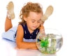 The little girl looks at the fish that floats in the aquarium. Royalty Free Stock Photo