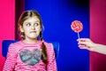 A girl looks with interest at the candy that is being offered to her.