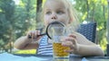 Little girl looks into the lens around. Close-up of blonde girl studying the world around her looking at it through magnifying
