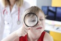 Little girl looks through magnifying glass in background is doctor