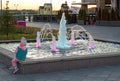 Little girl looks at the fountain at sunset on the Embankment of the city