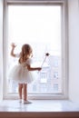 Little girl looks out window waits for Santa Claus
