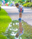 Little girl looks in a puddle like a mirror