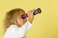 A little girl looks into a telescope or in a kaleidoscope. Royalty Free Stock Photo