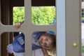 Little girl looks into window in house on children playground