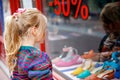 Little Girl looks at the window near the shopping center. Adorable happy child looking on shoes in store window. Royalty Free Stock Photo